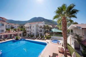 a swimming pool with a palm tree and some buildings at Sea Breeze Hotel and Apartments in Oludeniz