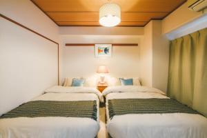 two twin beds in a room with a lamp at Meee Kameari in Tokyo