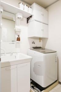 uma casa de banho branca com um lavatório e um espelho em Meee Kameari em Tóquio