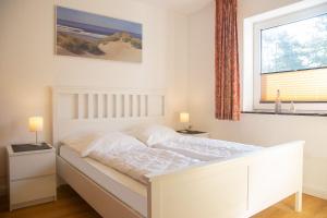 ein weißes Bett in einem Schlafzimmer mit einem Fenster in der Unterkunft Schöne Aussichten - Strandnah gelegen in Sankt Peter-Ording