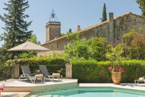 a pool with two chairs and an umbrella next to a building at Chateau de Varenne in Sauveterre