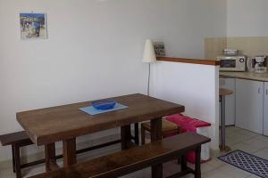 una pequeña cocina con mesa de madera y 2 bancos en Studio Option face à la mer, en Agon-Coutainville