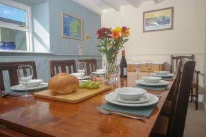 een houten tafel met borden, kommen en wijnglazen bij Spacious 3-Bedroom 3-bathroom country cottage in Haverfordwest