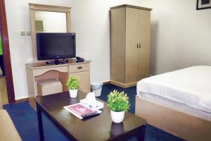 Zimmer mit einem Bett und einem Tisch mit einem TV in der Unterkunft Al Farhan Hotel Suites (Exit 15) in Riad