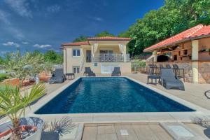 a pool in a backyard with chairs and a house at Villa Sole in Omišalj