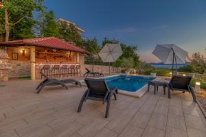 a patio with chairs and a pool and a pavilion at Villa Sole in Omišalj