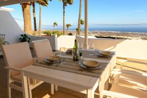 uma mesa de madeira com cadeiras e uma garrafa de vinho em VILLA PALMA LANZAROTE em Tías