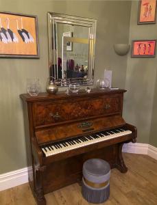 an old piano in a room with a mirror at The White House Hotel in Newquay