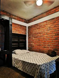 een slaapkamer met een bakstenen muur en 2 bedden bij Posada Don Jose in El Fuerte