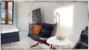 sala de estar con silla de cuero negro y TV en Bergvegen Guesthouse Aalesund, en Ålesund