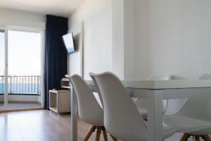 a dining room with a white table and white chairs at Apartamentos La Mar in Benidorm