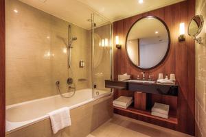a bathroom with a tub and a sink and a mirror at AMERON Hamburg Hotel Speicherstadt in Hamburg