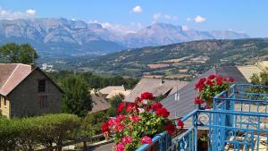 un balcon bleu avec des fleurs et des montagnes en arrière-plan dans l'établissement Les Fauvettes, à Saint-Léger-les-Mélèzes