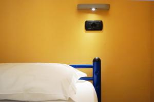 a bedroom with a yellow wall with a bed and a light at Hi! Ostello Milano in Milan +83 photos