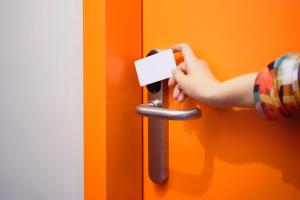 a person unlocking a door with a piece of paper at Hi! Ostello Milano in Milan