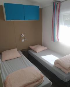 two beds in a room with a blue cabinet at Mobile Homes by KelAir at Camping Sol a Go Go in Saint-Hilaire-de-Riez