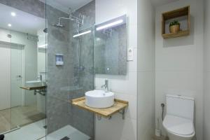 een badkamer met een wastafel en een glazen douche bij ROSE Apartamentos in Granada