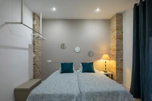 a bedroom with a large bed with blue pillows at ROSE Apartamentos in Granada