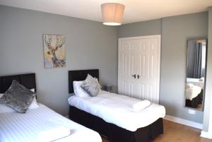 a bedroom with two beds and a mirror at Kelpies Serviced Apartments- Campbell in Pumpherston