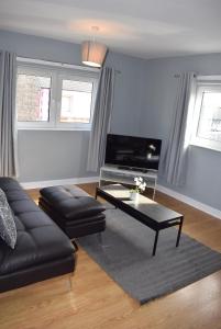 ein Wohnzimmer mit einem Sofa und einem Couchtisch in der Unterkunft Kelpies Serviced Apartments- Campbell in Pumpherston