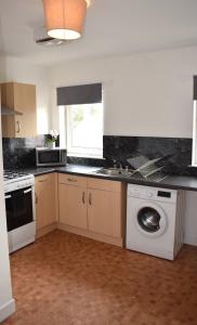 a kitchen with a sink and a washing machine at Kelpies Serviced Apartments- Campbell in Pumpherston