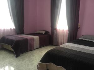 a bedroom with two beds and two windows at Cikgu CTZ Homestay (C) in Kampong Kubang Bemban
