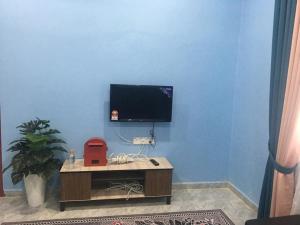 a room with a blue wall with a television on a table at Cikgu CTZ Homestay (C) in Kampong Kubang Bemban