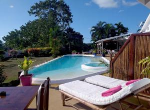 uma piscina com duas espreguiçadeiras e uma mesa em Villa Tonga Soa em Ambaro