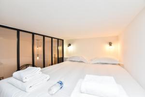 een slaapkamer met een wit bed en handdoeken bij CMG - VIGNOLES in Parijs