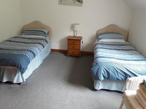 two twin beds in a room with a night stand at Lurig View B&B in Cushendall