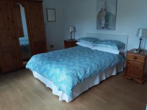a bedroom with a bed with a blue comforter at Lurig View B&B in Cushendall