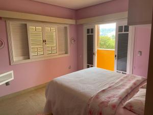 a bedroom with pink walls and a bed with windows at Casa de Campo Alto Padrao in Piracaia +16 photos