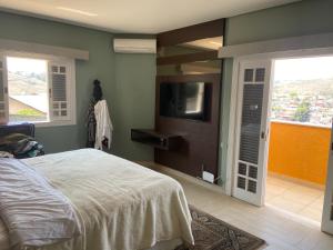 a bedroom with a bed and a flat screen tv at Casa de Campo Alto Padrao in Piracaia