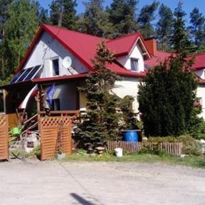 a house with a red roof with a tree in front of it at Pensjonacik Marzenie in Klonowo Dolne