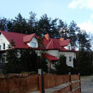 uma grande casa branca com telhados vermelhos atrás de uma cerca em Pensjonacik Marzenie em Klonowo Dolne