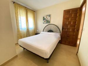 a bedroom with a large bed and a wooden door at Zahara Sol Villas y Apartamentos by QHotels in Zahara de los Atunes