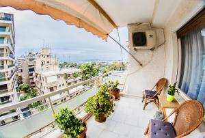 a balcony with a tv and chairs and plants at Flisvos Seafront-Marina apartment in Athens