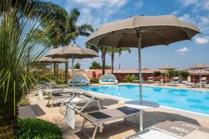a swimming pool with chairs and umbrellas next to a pool at Egò Salento in Galatina