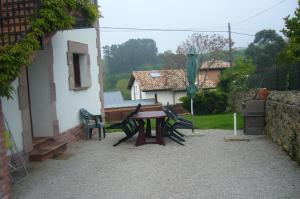 un patio con mesa y sillas junto a un edificio en Posada El Teju en Valdaliga 