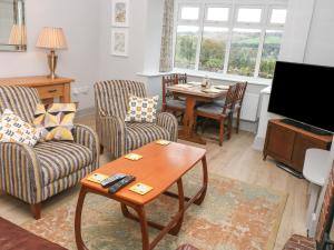 a living room with chairs and a table and a television at Coppice Hollow in Buxton