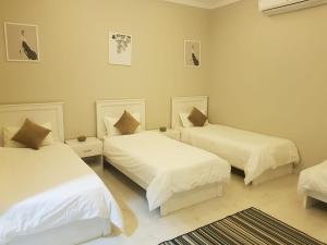 a bedroom with two beds with white sheets at Hidden Valley Farm Home AE in Bulaydah +69 photos