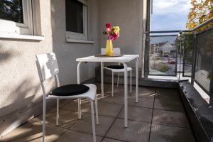 a table and two chairs and a vase with flowers on a balcony at FULL HOUSE Studios - KornhausDeluxe Apartment - Balkon, WiFi in Dessau