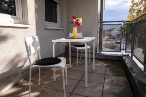 een tafel en twee stoelen en een vaas met bloemen op een balkon bij FULL HOUSE Studios - KornhausDeluxe Apartment - Balkon, WiFi in Dessau