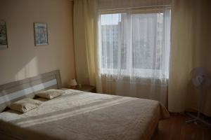 a bedroom with a bed and a window with a fan at Dzintari in Liepāja