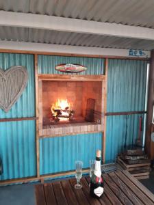 a fireplace in a room with a table and a bottle of wine at Little Camelot in Langebaan