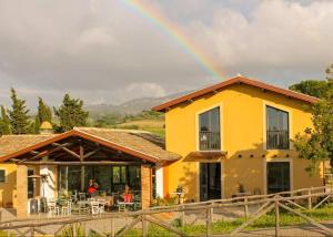 Un arcobaleno nel cielo sopra una casa gialla di Country House Erba Regina a Frascati