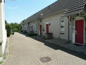 Une rangée de maisons avec des portes rouges dans une rue dans l'établissement Vacation home Zwaantje #DKR2, à Callantsoog