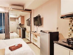 a room with a kitchen with a bed and a television at Apartemen grand kamala lagoon by 21 Room in Bekasi