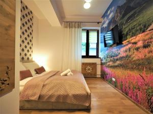 a bedroom with a bed and a tv on a wall at VIP Apartamenty TYTUS in Zakopane