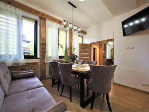 a dining room with a table and chairs and a couch at VIP Apartamenty TYTUS in Zakopane